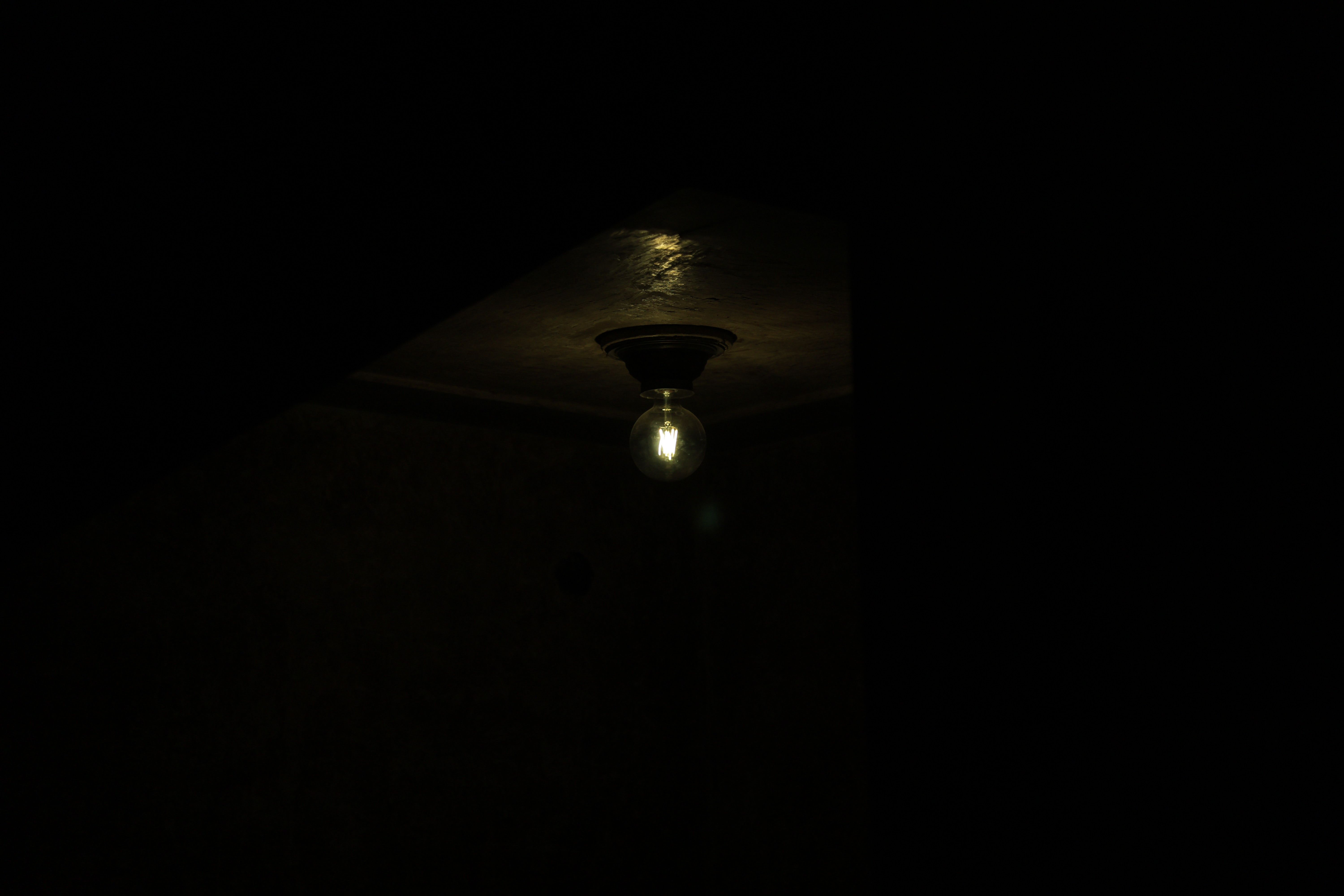 Single ceiling bulb burning unevenly in a dark room, the symptom behind most flickering lights calls