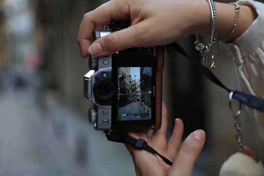 Photographer captures a charming street scene with a digital camera outdoors.