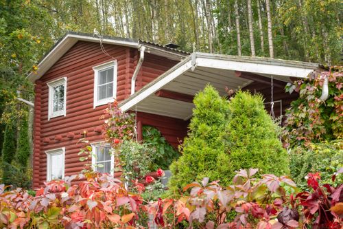Free Beautiful red cabin nestled in vibrant autumn forest, surrounded by lush greenery and colorful leaves. Stock Photo