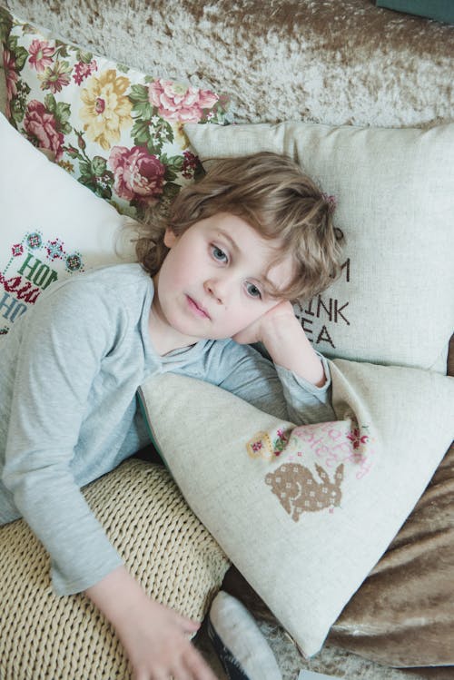 Girl in Gray Sweatshirt Leaning on White Pillow