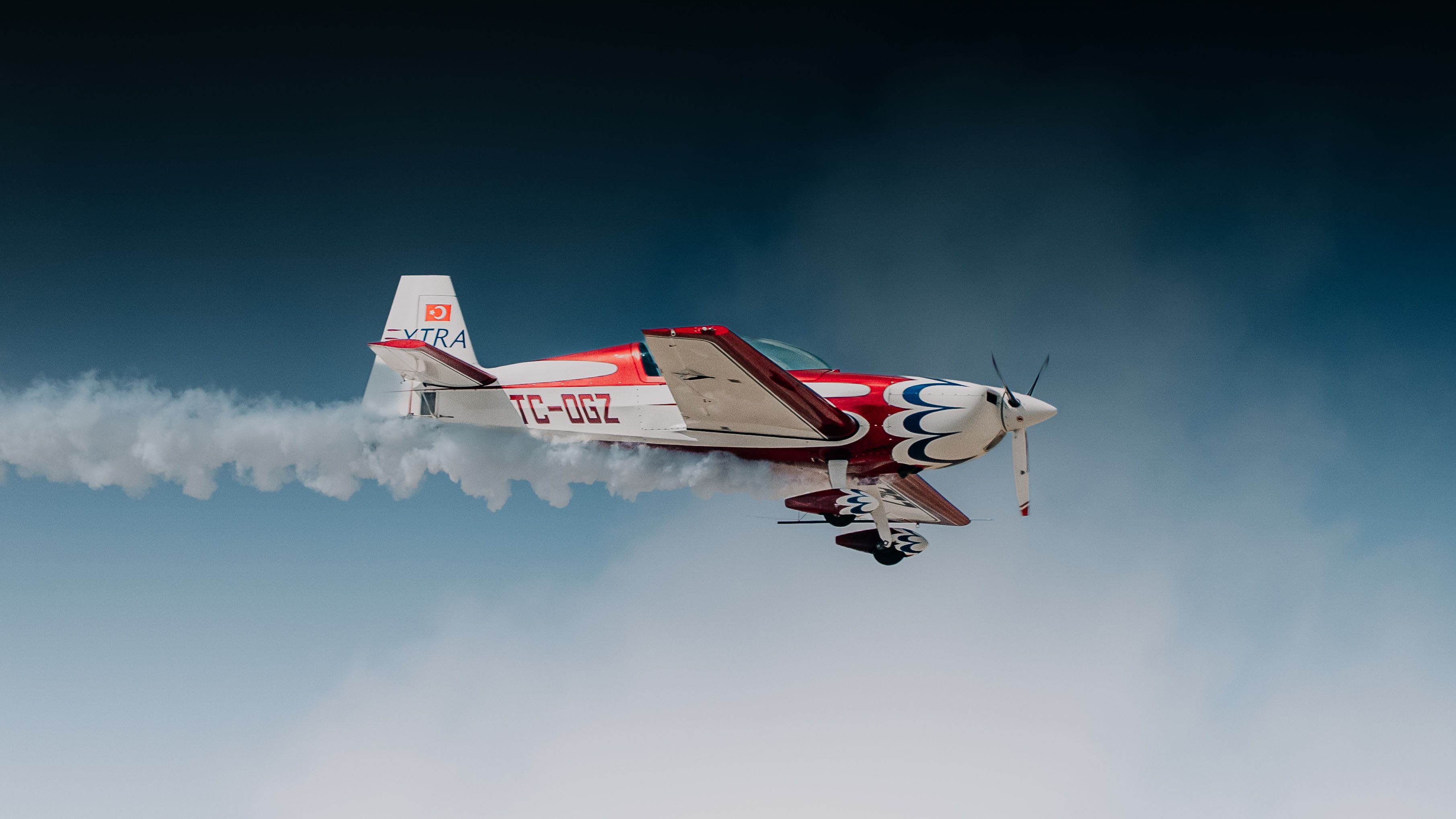 An aerobatic plane executing a stunning stunt with smoke trails against a clear blue sky.