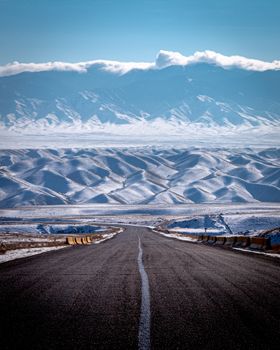 Panoramic view of a snowy road leading to the Tien Shan Mountains in Almaty, Kazakhstan.
