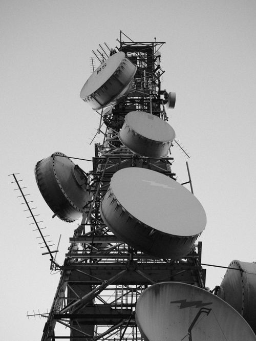 Free Black and white photo of a telecommunication tower with large satellite dishes, shot at daytime. Stock Photo