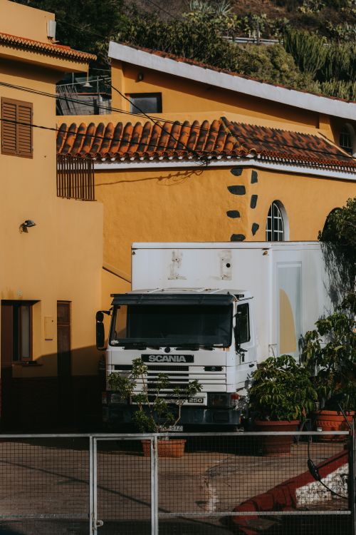 Free White delivery truck parked beside colorful Spanish architecture in San Sebastián de La Gomera. Stock Photo
