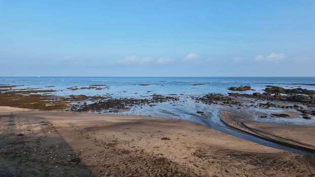 Expansive ocean horizon with rocky shoreline under a clear blue sky.