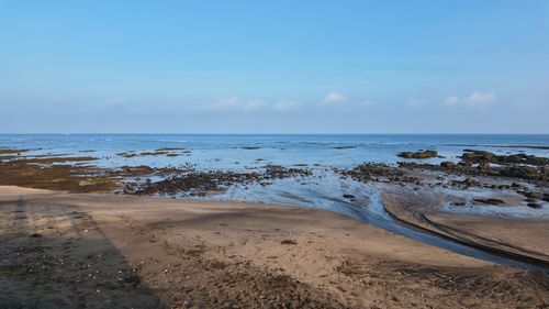 Free Expansive ocean horizon with rocky shoreline under a clear blue sky. Stock Photo