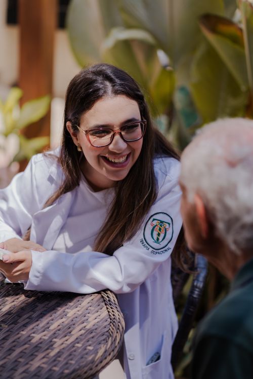 Free A friendly doctor in a white coat shares a warm moment outside with an older gentleman. Stock Photo