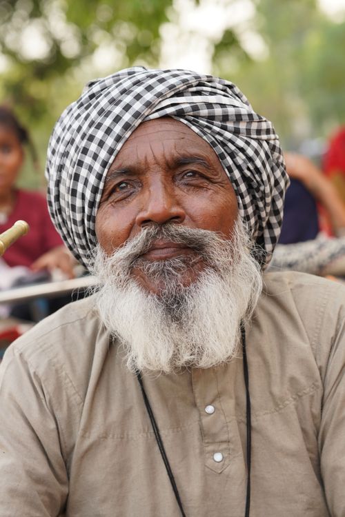 Free Portrait of an elderly man wearing traditional clothing and a checked turban outdoors. Stock Photo