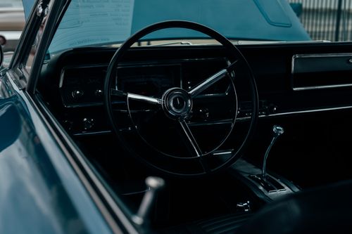 Free Vintage car interior featuring a classic steering wheel and dashboard in moody lighting. Stock Photo