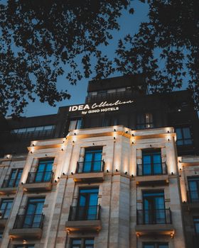 Stunning hotel exterior with warm lighting against a twilight sky, framed by tree branches. - Fotografer Sidoarjo