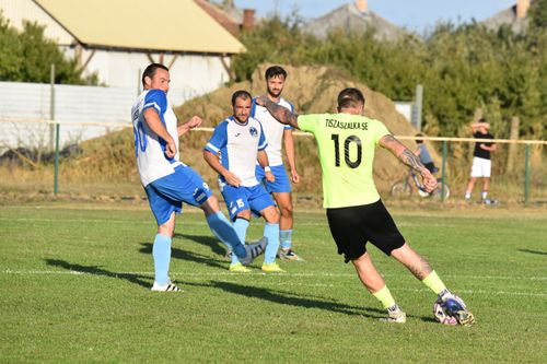 Free Players compete in an intense amateur football match on a sunny day, showcasing dynamic sports action. Stock Photo