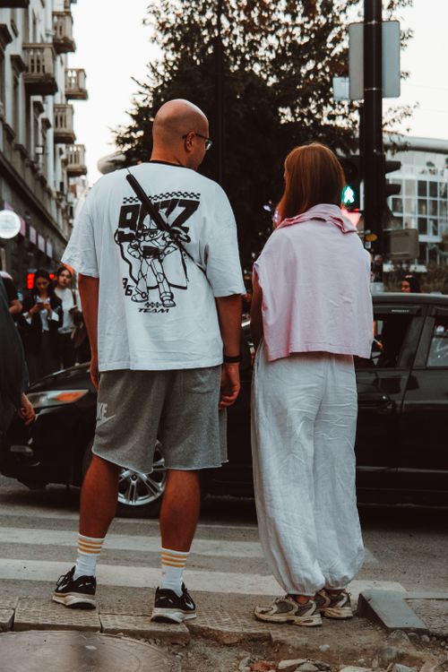 Free A fashionable couple standing at a crosswalk in the city during the day, blending modern and casual styles. Stock Photo