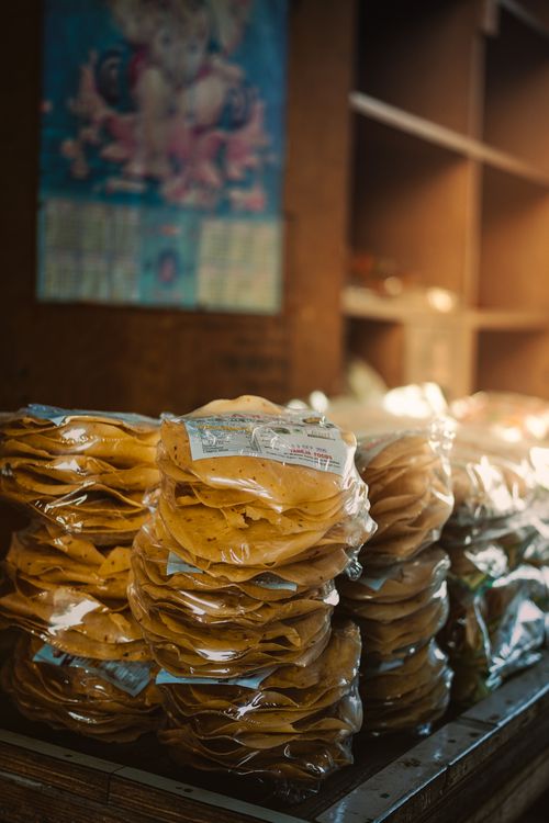 Free Stacks of packaged papadums displayed in a Moga, Punjab shop, capturing the local snack culture. Stock Photo