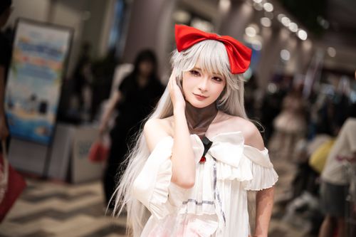 Free A striking cosplayer with white hair and red bow poses at an indoor event. Stock Photo