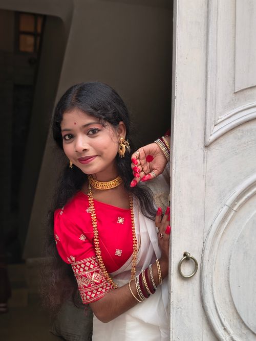 Free A South Asian woman in a saree with jewelry peeking through a doorway indoors. Stock Photo
