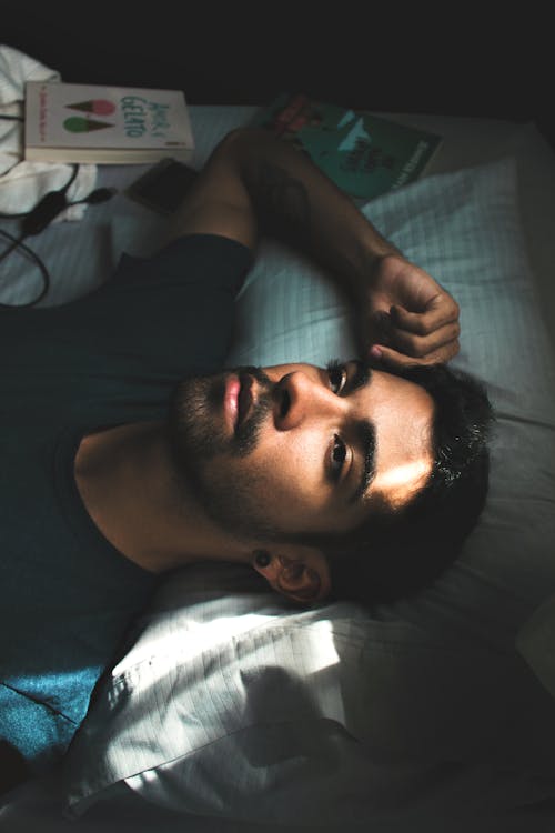 Man in Black Crew Neck T-shirt Lying on Bed