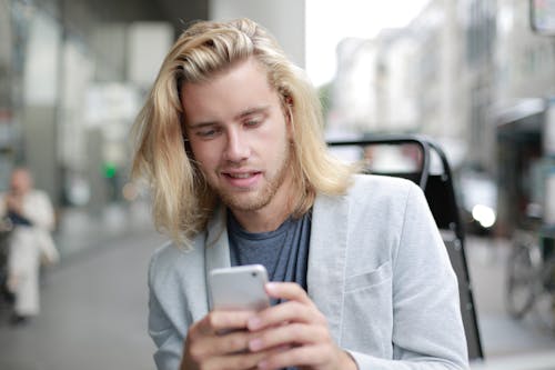 Man in Gray Coat Holding Silver Iphone 6