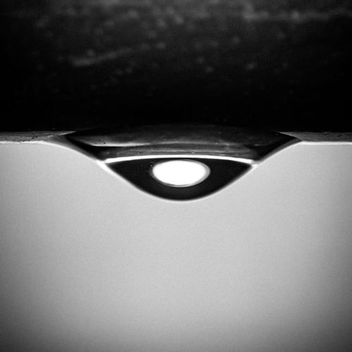Free Close-up of a water droplet reflecting light in black and white, creating a minimalistic abstract pattern. Stock Photo