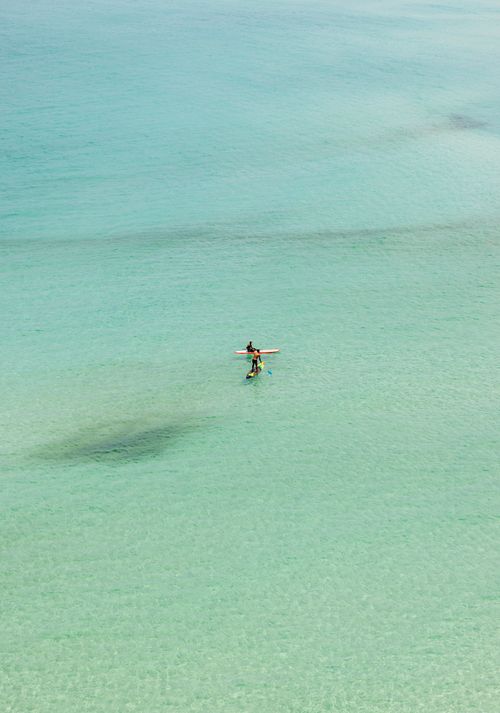 Free Aerial view of two kayakers paddling in crystal clear, turquoise ocean waters. Stock Photo