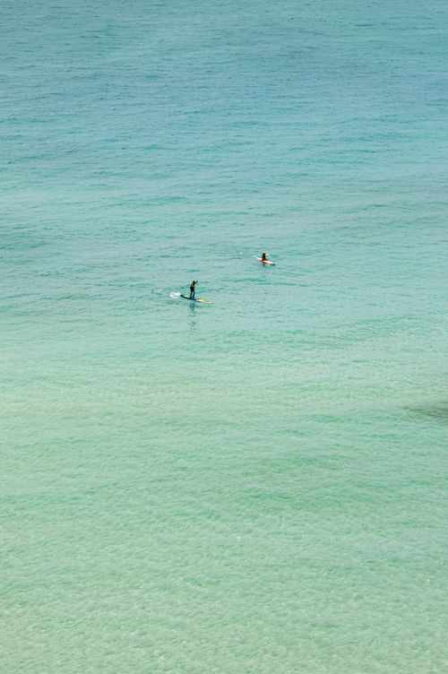 Free Two people enjoying paddleboarding on clear turquoise ocean waters, perfect for travel and adventure themes. Stock Photo
