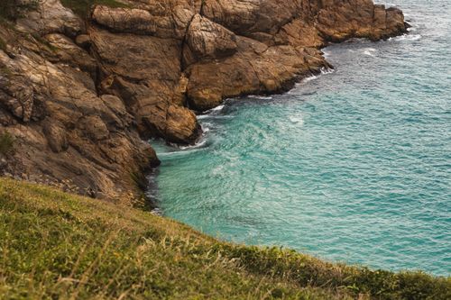 Free Dramatic view of rocky coastline with turquoise water and lush greenery, perfect for travel and nature themes. Stock Photo