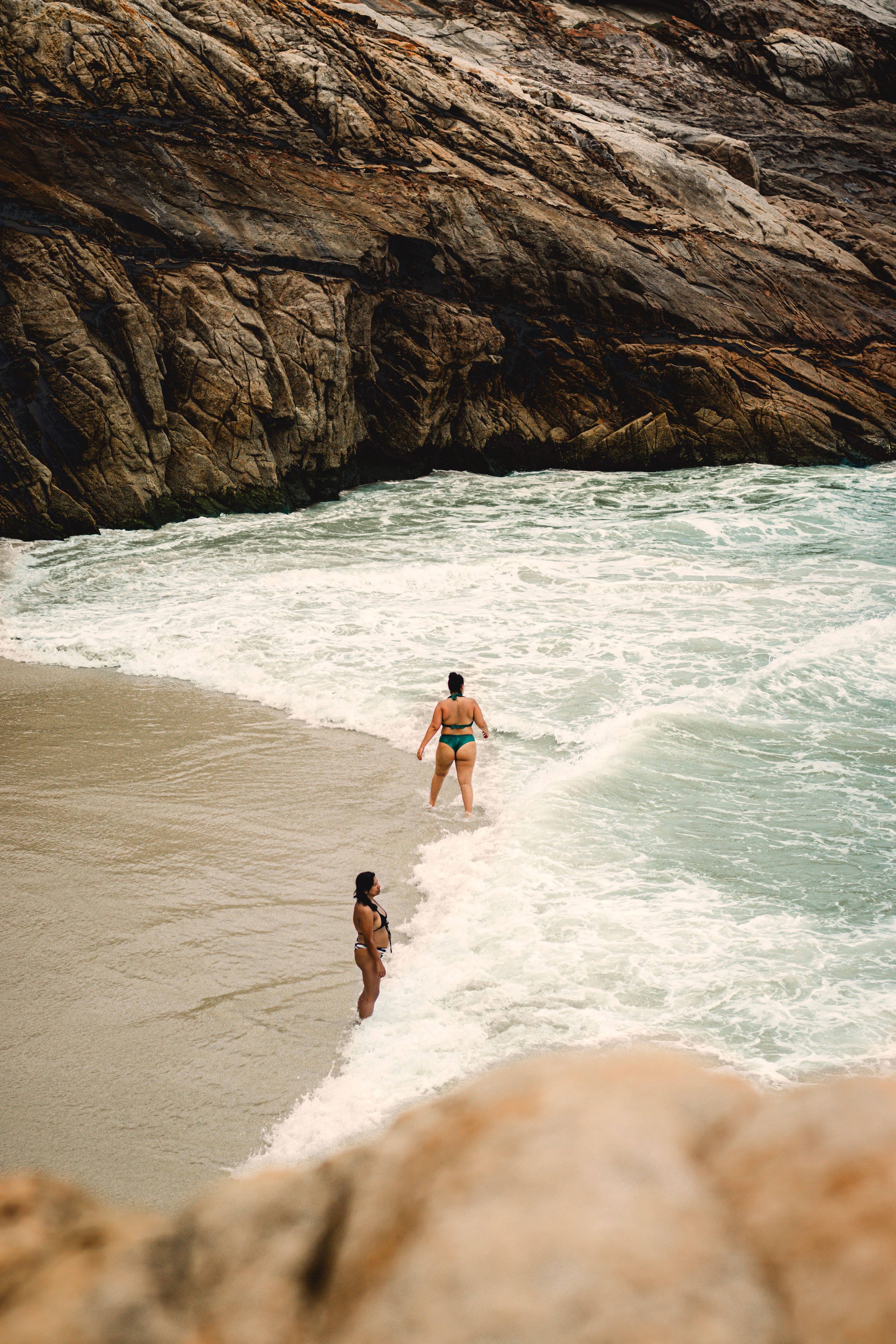 Duas pessoas aproveitando um mergulho perto de falésias rochosas em uma praia pitoresca.