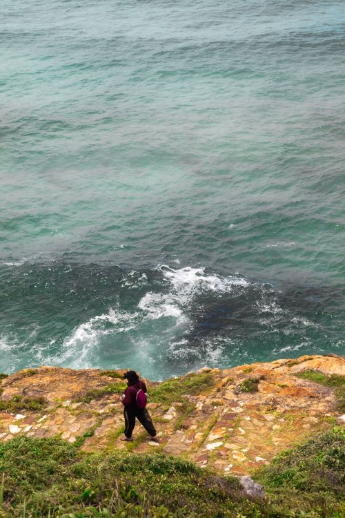 Free A woman strolls along a scenic ocean cliff with waves crashing below in Brazil. Stock Photo