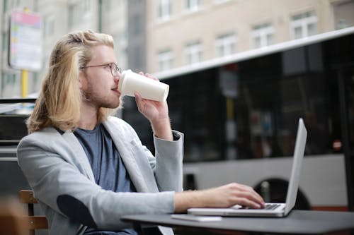 Free Man Drinking Coffee while Working on His Laptop Stock Photo
