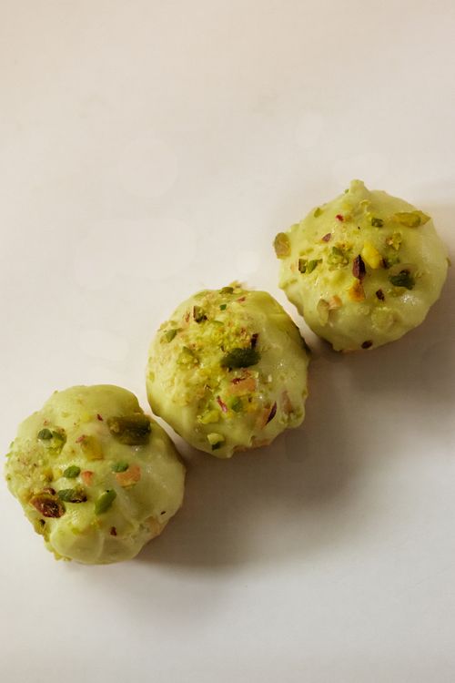 Free Three choux pastries topped with pistachios on a neutral background. Stock Photo