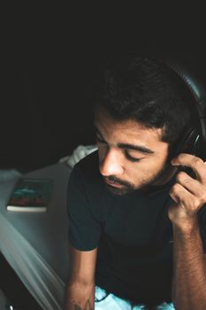 室内灯光柔和，一个戴着耳机的年轻人正专心听音乐