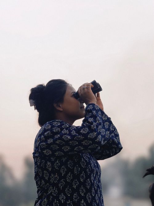 Free Side view of a woman using binoculars, immersed in nature during the daytime. Stock Photo