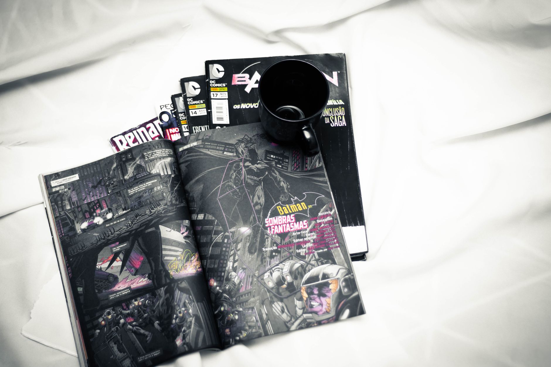 Open comic book and mug resting on a bed for a cozy reading vibe.