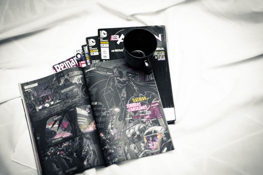 Open comic book and mug resting on a bed for a cozy reading vibe.
