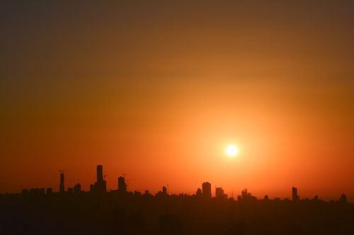 Free A breathtaking view of a city skyline silhouetted against a vivid sunset, capturing serene urban beauty. Stock Photo