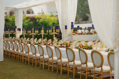Free An elegantly decorated outdoor wedding reception with a long table set amidst a lush garden. Stock Photo