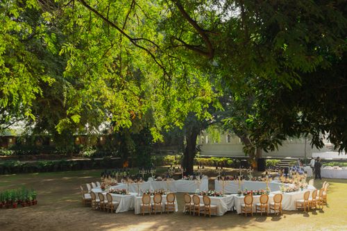 Free Beautifully set outdoor wedding table arrangement, in a lush garden beneath green trees, creating an elegant event atmosphere. Stock Photo