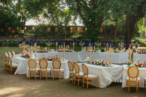 Free Beautiful outdoor event setup with tables, chairs, and floral decorations under lush green trees. Stock Photo