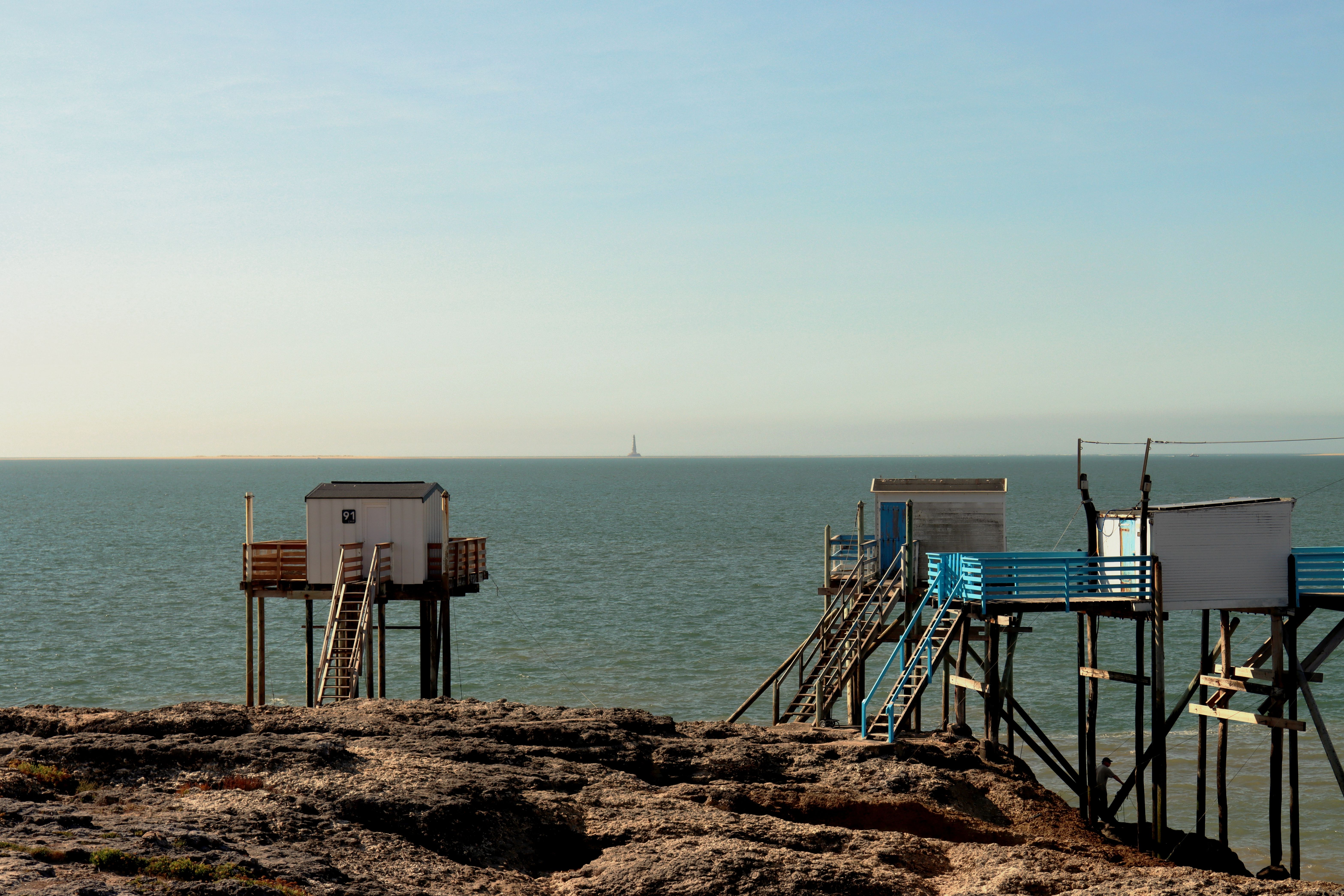 Rustic fishing huts on stilts over the ocean in Saint-Palais-sur-Mer, France, at daytime.