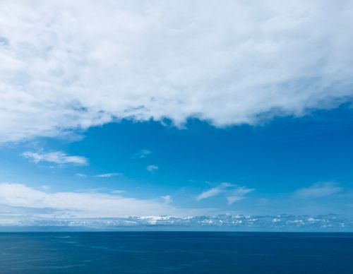 Free Breathtaking view of the ocean meeting the blue sky with scattered clouds above. Stock Photo