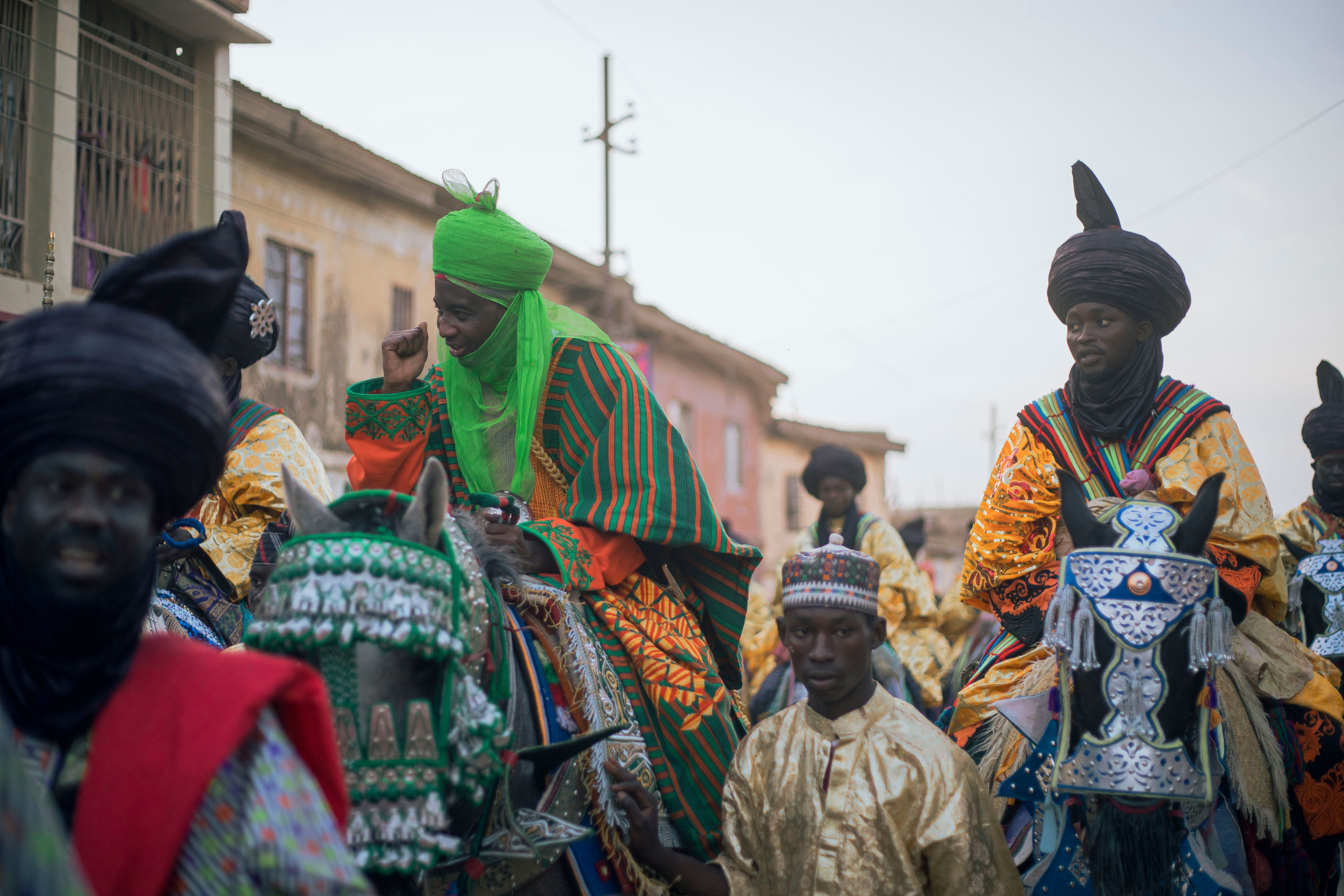 Vibrant parade of traditional horse riders in cultural attire during daytime in Nigeria.