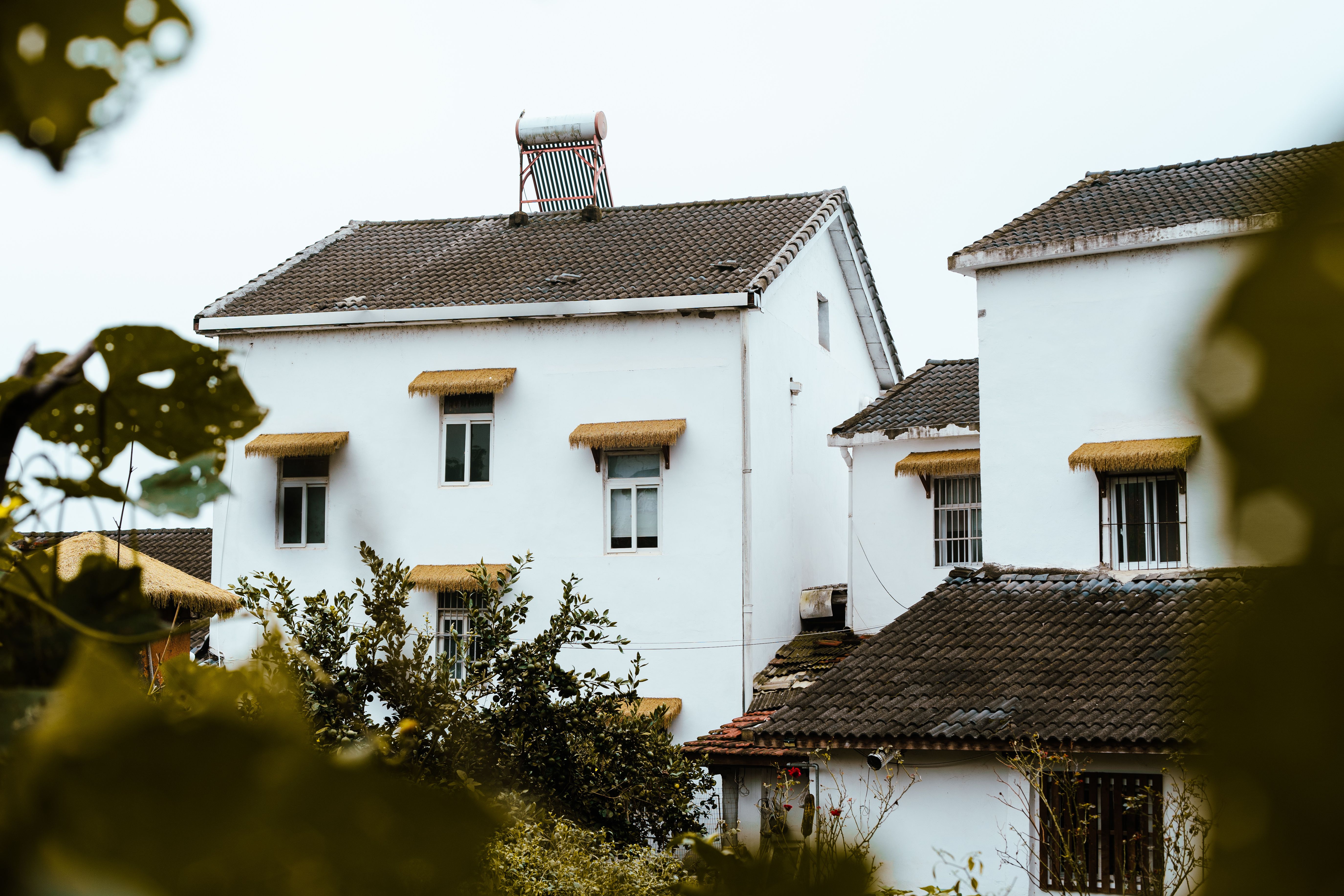 White village houses with thatched roofs and a rooftop solar panel.