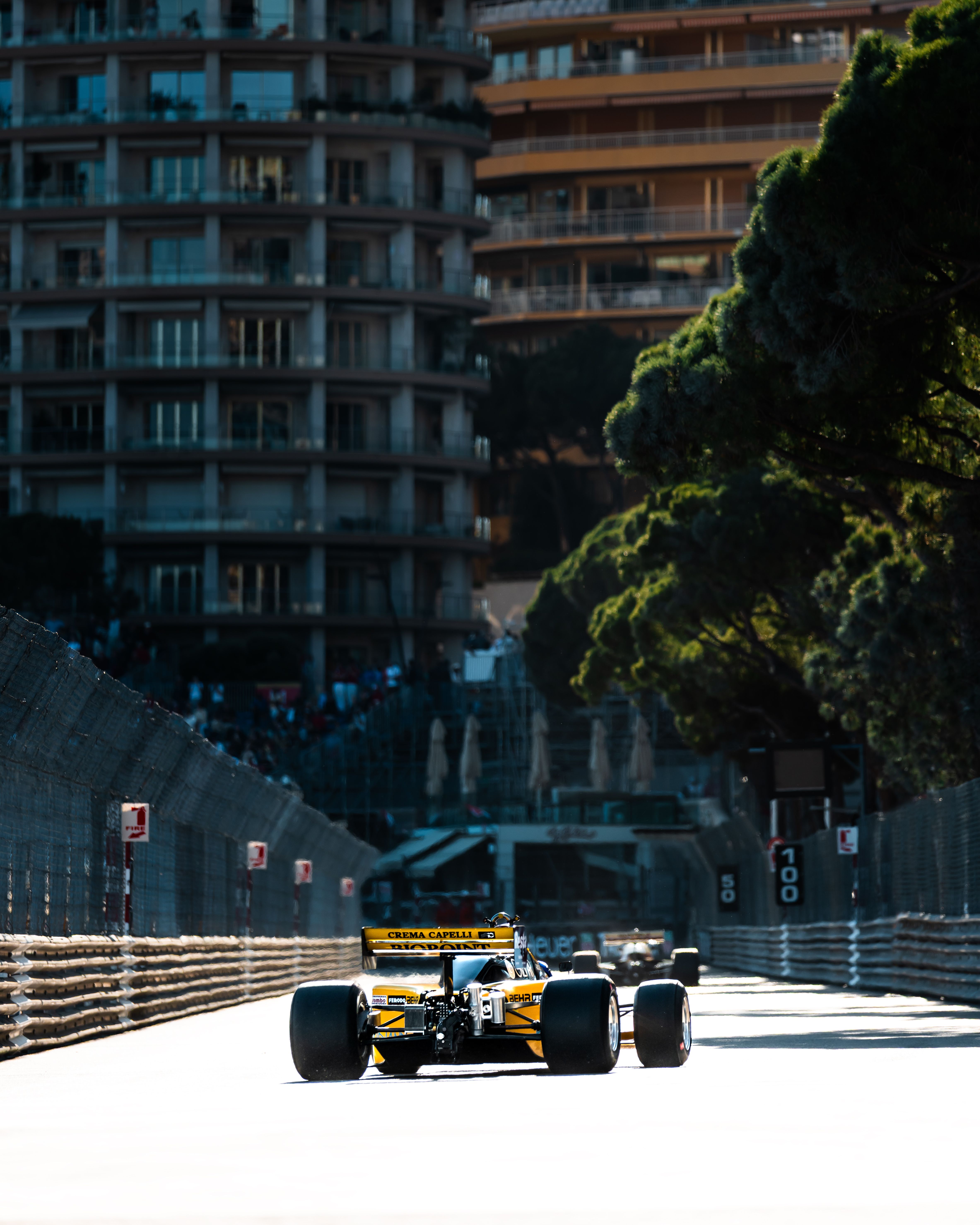 Yellow Formula 1 car racing on the iconic streets of Monaco, surrounded by tall buildings.