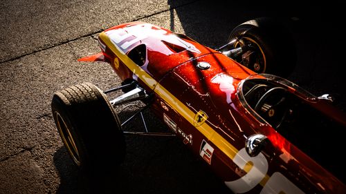 Free Vintage red race car with iconic logo illuminated by sunlight. Stock Photo