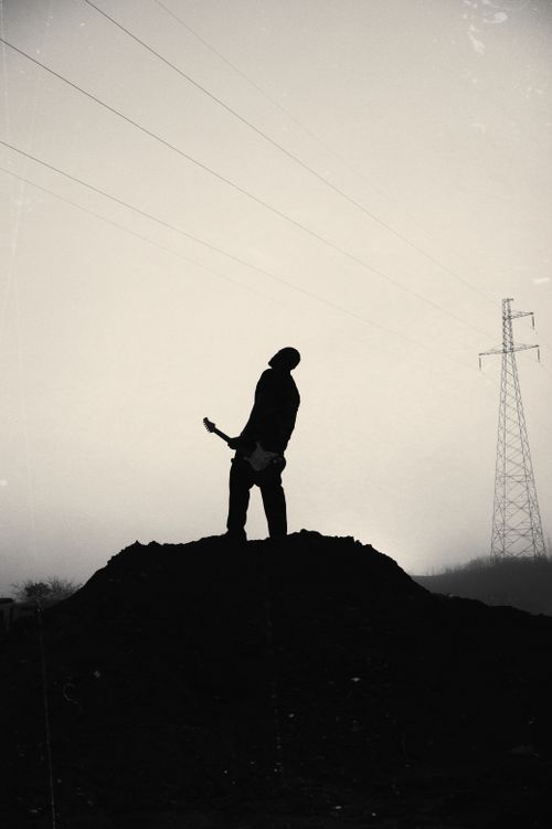 Free Silhouette of a musician playing guitar atop a mound at dusk, Federal Capital Territory, Nigeria. Stock Photo