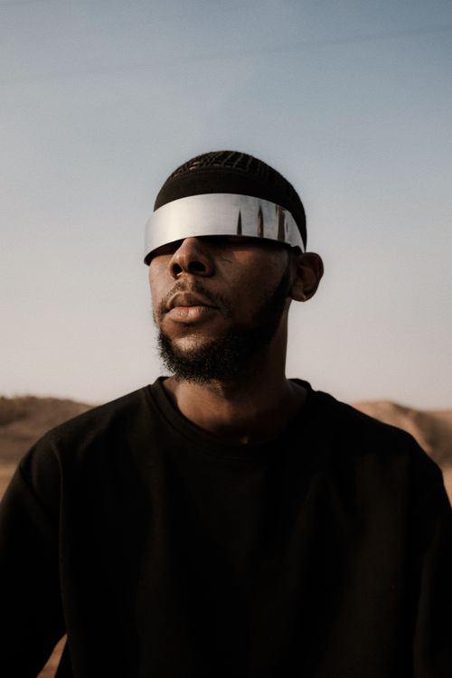 Free A man in futuristic eyewear stands in the Nigerian desert under a clear sky. Stock Photo