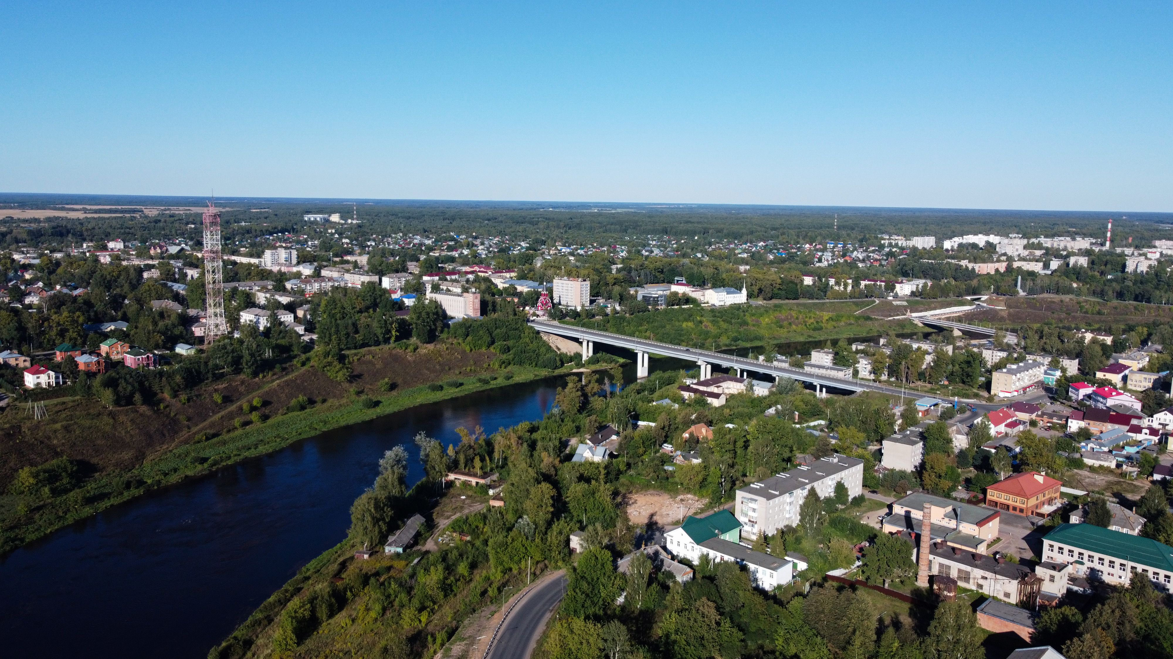Aerial view of Rzhev cityscape featuring a bridge over the Volga River in summer.