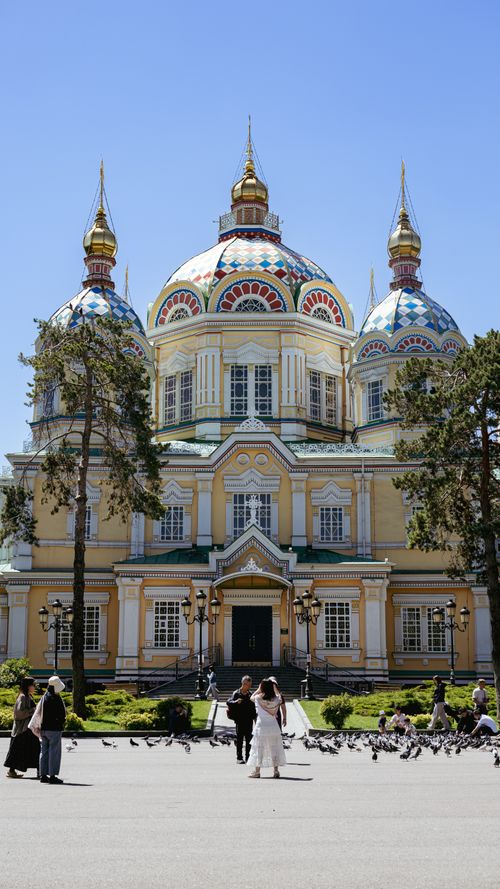 Free Wedding couple and visitors outside the colorful Zenkov Cathedral in Almaty, Kazakhstan. Stock Photo