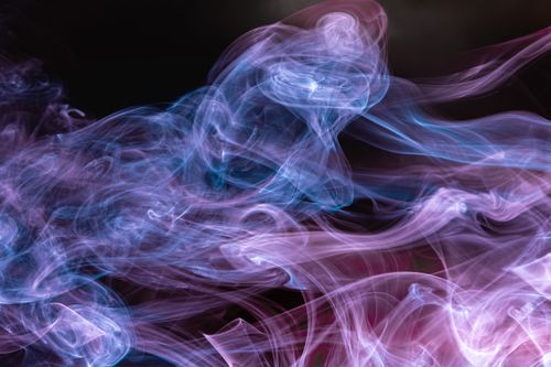 Free Abstract image of colorful smoke swirling in front of a dark background, creating a cosmic effect. Stock Photo
