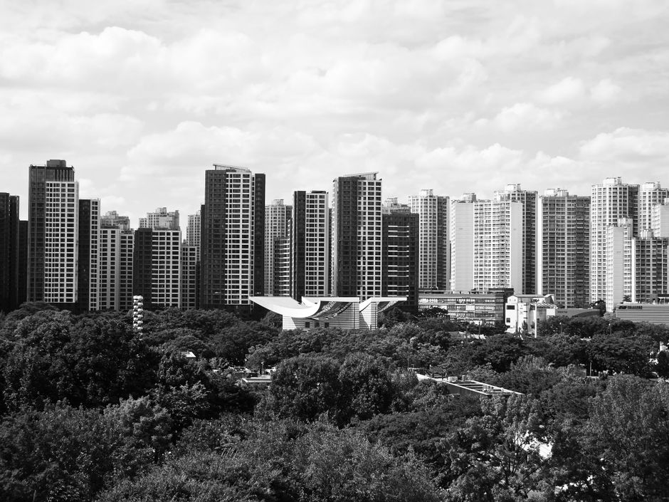 Black and white panorama of Seoul's skyline, showcasing modern high-rise buildings under a cloudy sky.