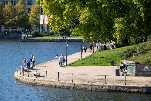 Free Tourists enjoying a sunny day at Binnenalster, Hamburg with lush greenery. Stock Photo